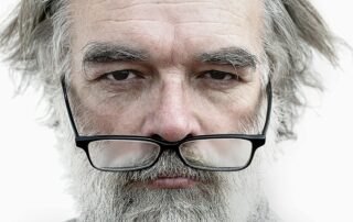 Älterer Mann mit Brille blickt nachdenklich in die Ferne – Symbolbild für die Ursachen und Auswirkungen des Grauen Stars auf das Sehvermögen.