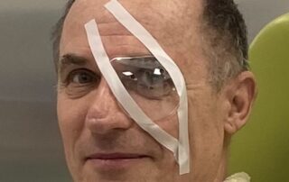 Patient nach Grauer Star Operation mit Augenverband bei der postoperativen Nachsorge